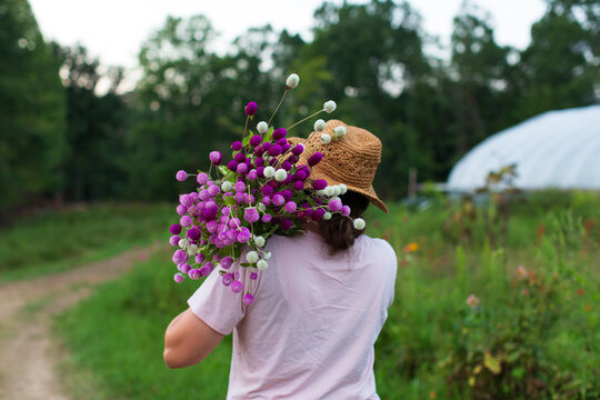 Woman in straw hat carries freshly picked flowers