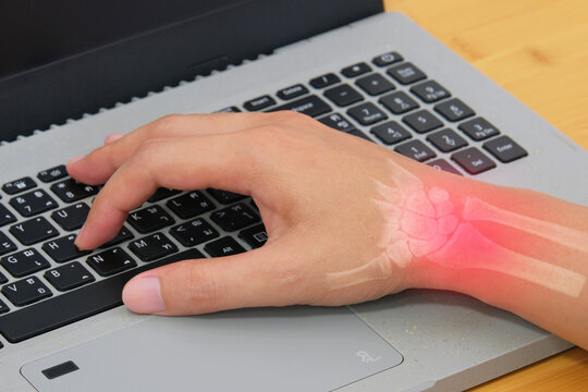 Wrist pain showing a worker using a computer keyboard with highlighted wrist anatomy for carpal tunnel and repetitive strain treatment concepts.