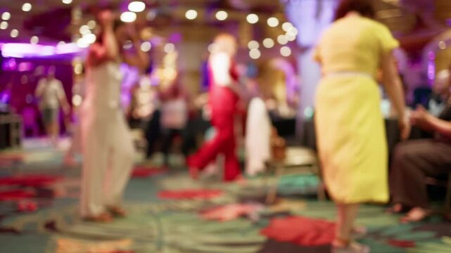 Blurred guests dancing in colorful party hall with bright lights and lively social atmosphere