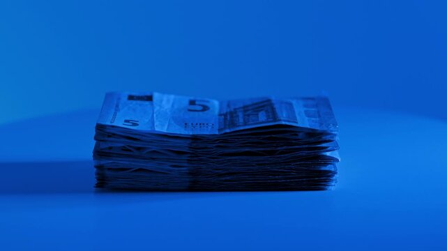 Rotating euro cash stack under blue light symbolizes finance, savings and wealth