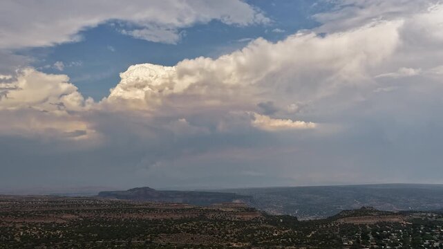 4K aerial timelapse of a massive pyrocumulus cloud billowing from the Frijoles Fire in Santa Fe County. The towering smoke plume dominates the sky over a vast New Mexico canyon landscape.
