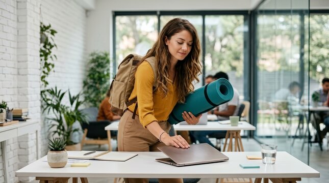 A businesswoman closing her laptop at the office before heading to a yoga class.