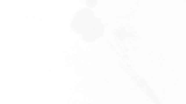 Black Ink Bleeding and Spreading Over White Surface Texture.
