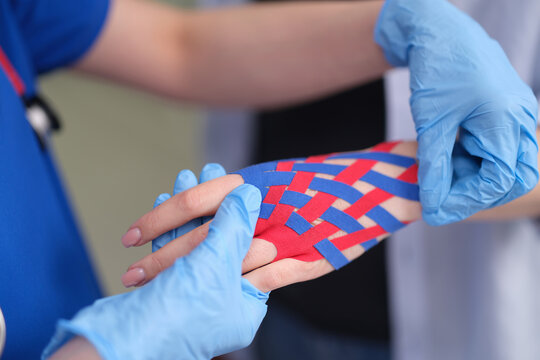 Doctor treating patient injured hand with kinesio tape closeup.Treatment of injuries and damage to joints and ligaments using kinesiotherapy 