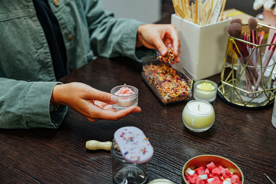 Participants work together at a candle making master class, using jars, wicks, wax pieces, tools, brushes, and decorative materials around a wooden table
