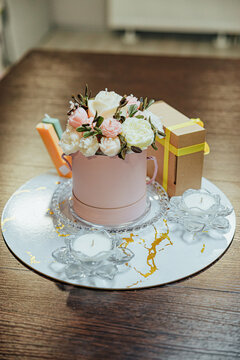 Elegant floral candle arrangement in a pink round box displayed with wrapped gift boxes and white tealight candles on a reflective decorative tray
