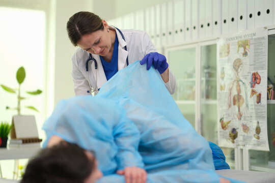 Proctologist examines rectum of woman with hemorrhoids at clinic. Surgical treatment of rectal problems concept
