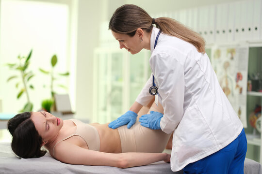 Doctor palpates abdomen of sick woman with acute abdomen in clinic. Diagnosis of appendicitis 