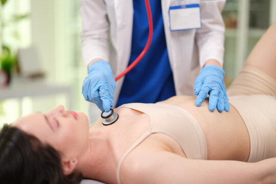 Doctor listens to patient heart and lungs with stethoscopes in clinic closeup. Diagnostics of internal diseases