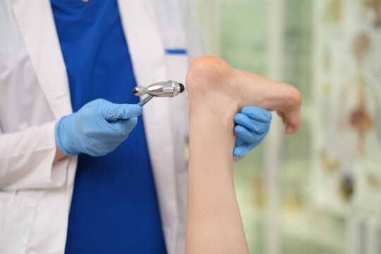 Neurologist checks pathological symptoms on patient leg with hammer closeup. Diagnosis and treatment of diseases of nervous system
