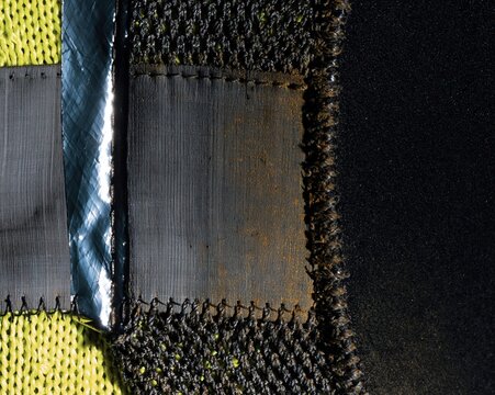 Close up of a technical textile junction with neon yellow knit and reflective tape, featuring tactile abraded textures for industrial design and marketing layouts