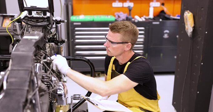 In a vibrant workshop, a focused technician meticulously inspects and adjusts engine parts, showcasing his craftsmanship and attention to detail.