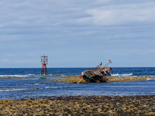 The wreck of the Sovereign Fishing Boat on the rocks at Cairnbulg Point Navigation Beacon in Fraserburgh Bay, with abandoned and discarded Fishing nets beside it. © Julian