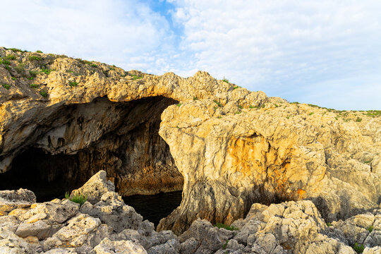 Natural rock archway carved by the sea, revealing a dark cave entrance