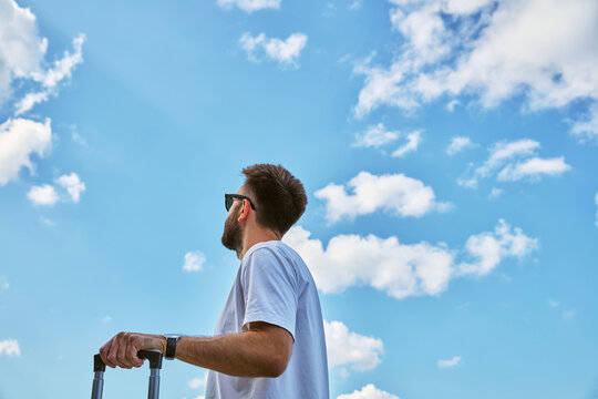 Low Angle View of Man with Suitcase Looking at Blue Sky