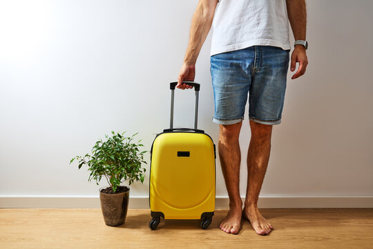 Low Section of Barefoot Man Standing with Yellow Suitcase at Home