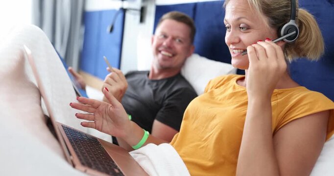 In a cozy room, two friends share joyful moments while using laptops and headsets. Their laughter echoes as they enjoy conversations, creating lasting memories together.