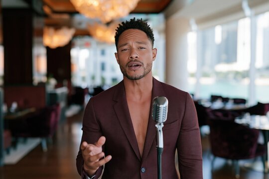 Male vocalist in burgundy suit with vintage microphone in upscale lounge for music poster and promotional background