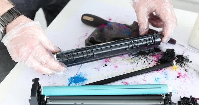 Hands skillfully refill a toner cartridge, surrounded by splashes of color and tools. This workshop reveals the art of recycling cartridges while maintaining cleanliness and vibrant results.