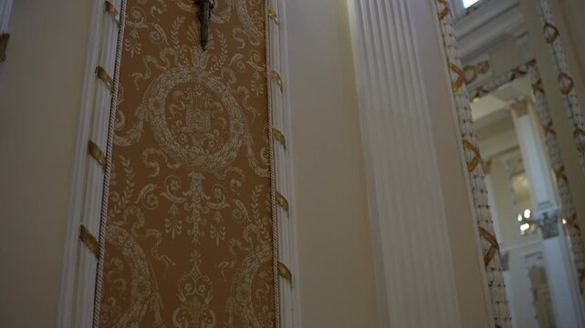 Ornate damask wall panel framed by carved moulding and gold leaf accents in elegant historic interior, with interior, panel, damask, moulding detail, showing rope, gilding, gold, pilaster context