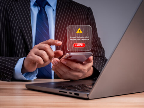 Business professional in suit cancels suspicious account verification request alert on smartphone at office. Phishing prevention, fraud awareness and secure decision-making in the workplace concept.