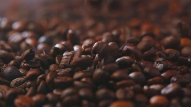 Freshly roasted coffee beans falling in slow motion onto a bed of beans, capturing rich texture, freshness and an irresistibly indulgent coffee moment in cinematic detail.