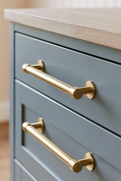 Close-up of modern brushed brass cabinet handles on grey drawers, showcasing home renovation and interior design