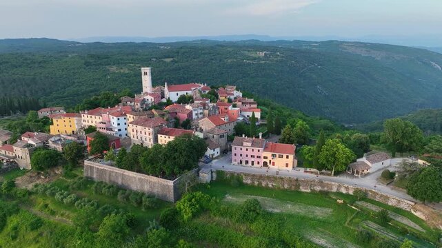 Cinematic aerial drone shot of Oprtalj hilltop medieval town in Istria Croatia during summer with historic stone houses, narrow streets, surrounding hills and authentic European scenery