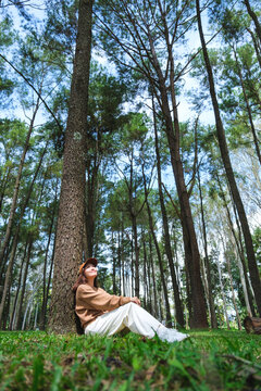 Vertical portrait image of a woman sitting and relaxing in the park