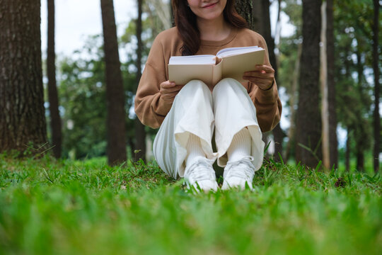 Closeup image of a woman reading a book while sitting in the park