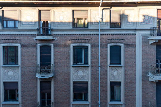 Facciata in mattoni di edificio storico con finestre simmetriche, decorazioni geometriche e luce naturale che evidenzia texture e dettagli architettonici. Ideale per temi urbani e architettura