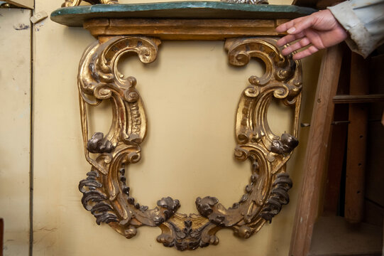 Consolle antica con ricchi intagli dorati e piano in marmo, esaminata durante il restauro. Dettagli barocchi e artigianato raffinato ideali per temi di arte, antiquariato e decorazione.