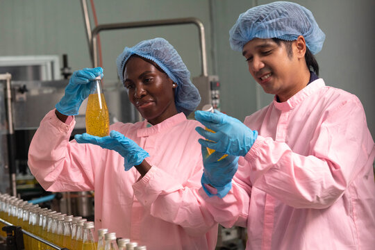 Two factory workers monitoring cold drink bottles on production line at drinks production plant.
