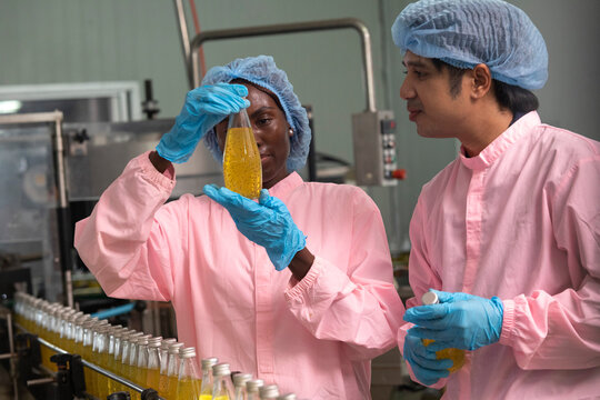 Two factory workers monitoring cold drink bottles on production line at drinks production plant.