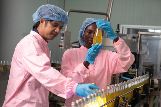 Two factory workers monitoring cold drink bottles on production line at drinks production plant.