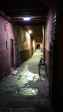Marrakech, morocco. August 8, 2026. Dark and atmospheric narrow street in the ancient medina of marrakech, morocco. A mysterious figure walking in the background at night
