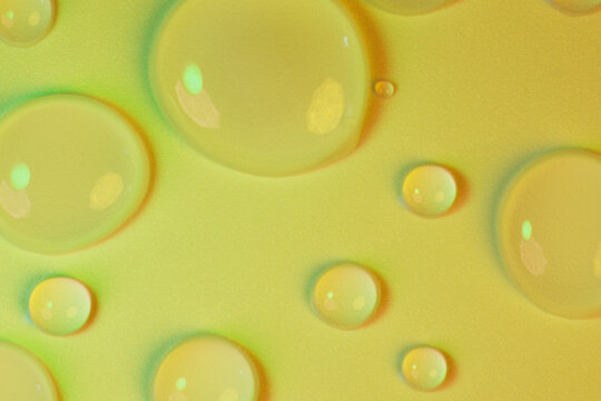 Macro shot of clear round water drops with light reflections on olive green golden textured surface for organic skincare, herbal serum, botanical face oil, cica extract, and natural eco spa backdrop.