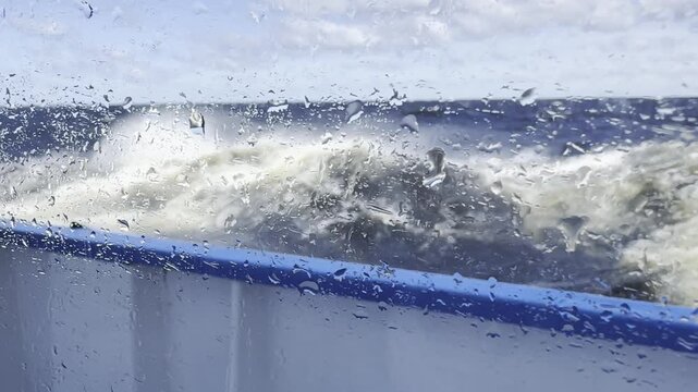 A powerful storm on Lake Onega viewed through a cruise ship porthole, with large waves breaking against the vessel and rain and spray creating a dramatic scene beneath a rainbow.