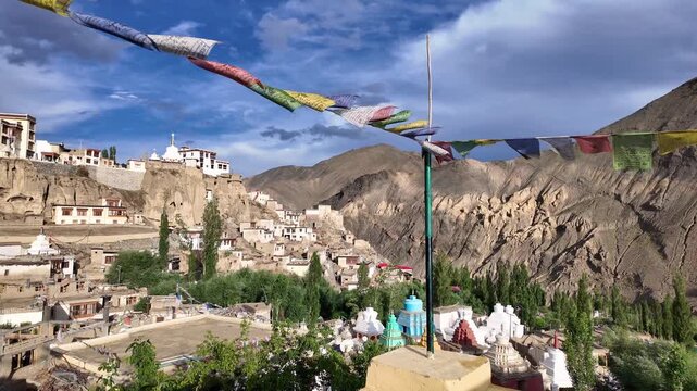 Lamayuru, India: Panoramic footage of village and famous Tibetan Buddhism Lamayuru monastery or Yuru Gompa in Ladakh Himalayan mountains in India through prayer's flags blown by the wind on sunny day