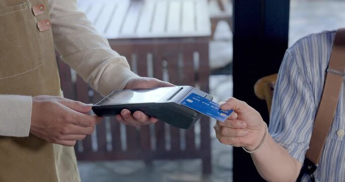 Senior asian retiree woman pays restaurant bill with blue credit card during brunch reunion, warm cafe meetup, friend gathering, social connection, supportive lunch after long absence, slow paced clip