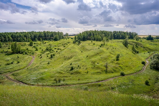 Summer landscape of green hills with a dirt road near Ishutinskaya Mountain, Tula region of Russia