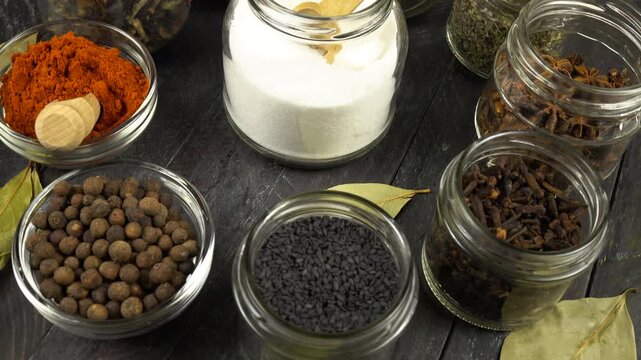 Different shapes and sizes of empty glass jars filled spice and herb for storage stand on a black wooden board, top view, Reuse of glass jars, kitchen organization