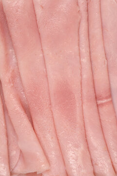 Full frame macro view showing the rough texture and fine details of overlapping thin slices of pink cooked deli ham