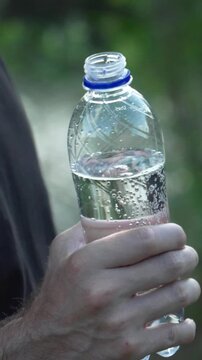 Open plastic water bottle close up in hand vertical video, hydration concept reel