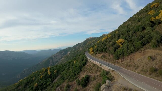 Cinematic FPV drone footage along a mountain road with yellow blooming Mount Etna broom covering the hillsides, Canyon Gorropu, Baunei, Sardinia, Italy.