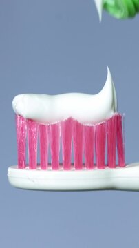 Close-up of toothpaste being squeezed onto a pink toothbrush head