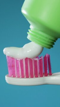 Close up of toothpaste being squeezed onto a pink toothbrush for dental hygiene