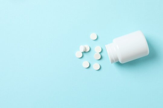 Pills with white medicine bottle on blue background
