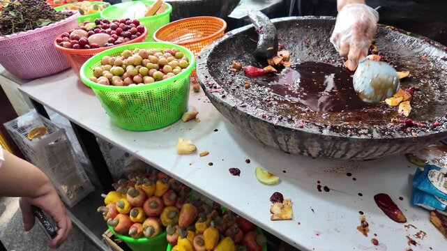 Vendor preparing traditional street food with fruits and spices in a large bowl.