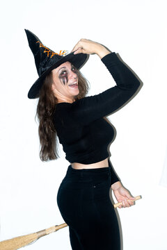 Happy woman dressed as a witch posing with broom for Halloween